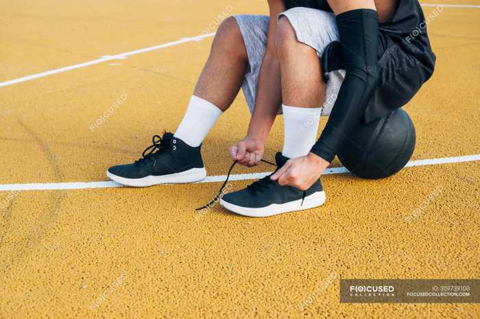 focused 309739100 stock photo young man basketball court fixing - Tips Menjaga Grip Sepatu Atlet di Lantai Parket Lapangan Basket